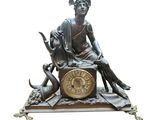une statue en bronze représentant une femme assise sur une horloge