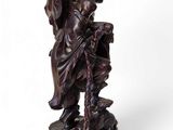 an old wooden statue of a man holding a staff