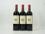 trois bouteilles de vin rouge sont alignées sur une surface blanche