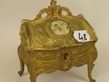 a gold clock sitting on top of a small table