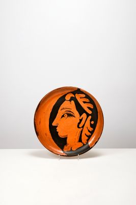 une assiette orange et noire sur laquelle est peint le visage d'une femme