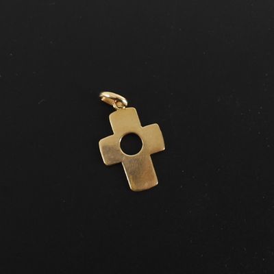a gold cross pendant on a black background