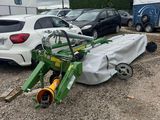 a green tractor parked in a parking lot next to other vehicles