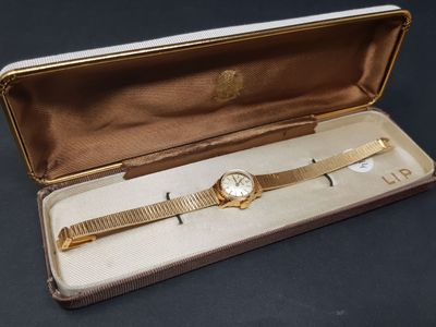 une montre en or dans un écrin posé sur une surface noire