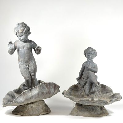 deux statues représentant un garçon et une fille assis sur un coquillage