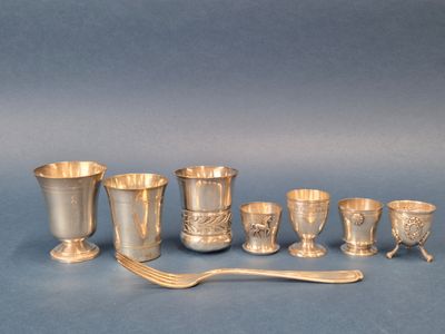 plusieurs tasses et cuillères en argent posées sur un fond bleu