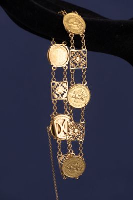 un gros plan sur la main d'une personne tenant un bracelet orné de pièces de monnaie