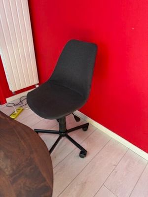 a black chair sitting in front of a red wall