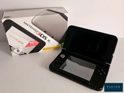 une Nintendo 3DS noire posée à côté d'une boîte sur une table
