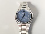 a silver watch with a blue face on a white surface