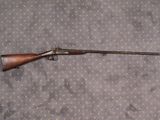 un vieux fusil au canon en bois posé sur un lit