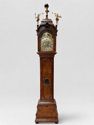 une grande horloge de parquet en bois, surmontée d'un pendule