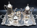 a silver tray that has a silver tea set on it