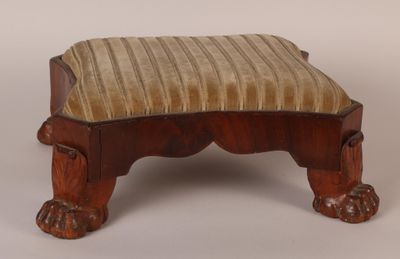 un petit tabouret en bois surmonté d'un coussin rayé