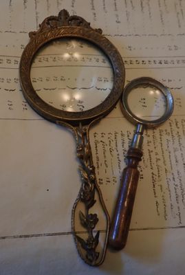 une loupe et une paire de ciseaux posés sur une feuille de papier