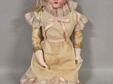 an old fashioned doll sitting on a white surface with a white background