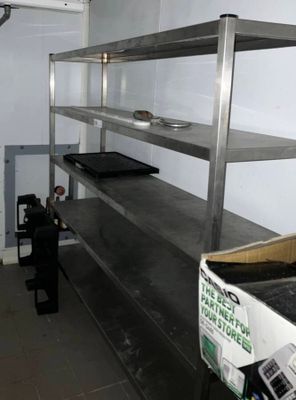 a man standing in a kitchen next to a metal shelf