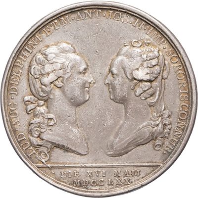 a close up of a silver coin with two women facing each other