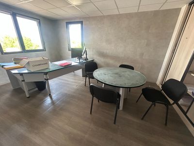 une pièce avec une table, des chaises et un ordinateur portable posé dessus