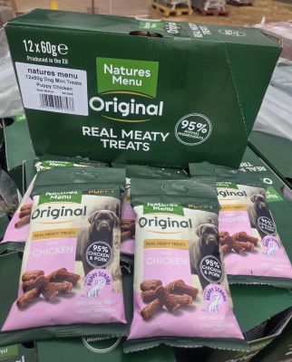 trois paquets de friandises pour chiens posés sur une pile de cartons