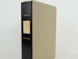 un vieux livre à la couverture noire posé sur une surface blanche