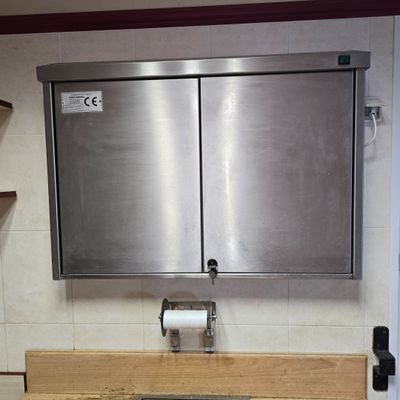 un lavabo en acier inoxydable dans une salle de bains, surmonté d'un miroir