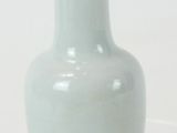 a small white vase sitting on a clear surface
