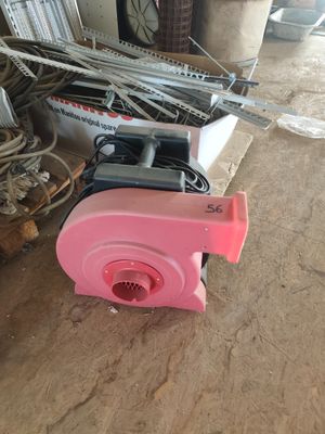 un souffleur rose posé par terre à côté d'un tas de vieilleries