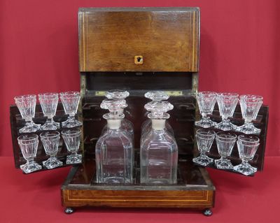 des bouteilles et des verres dans un coffret en bois posé sur un fond rouge