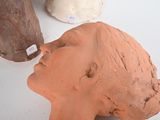three clay sculptures of a woman ' s head on a table