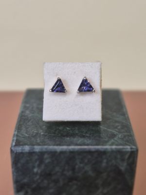 a close up of a pair of earrings on top of a marble block