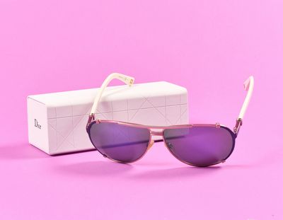 des lunettes de soleil dans une boîte posée sur une surface rose, avec un fond rose