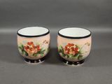 pair of hand painted porcelain egg cups with black rims