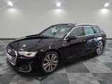L'Audi noire est garée dans une grande pièce au sol carrelé.