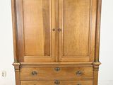 a wooden armoire with two drawers on top of it