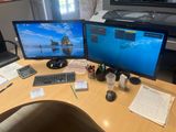 a desk with two monitors and a keyboard on it