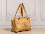 beige leather handbag on wooden table in front of white wall
