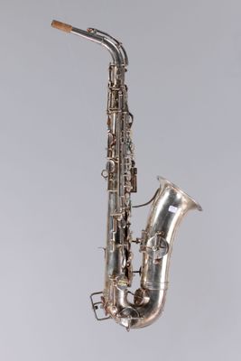 un vieux saxophone argenté posé sur une surface blanche