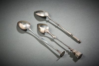 three silver spoons with handles on a table with a gray background