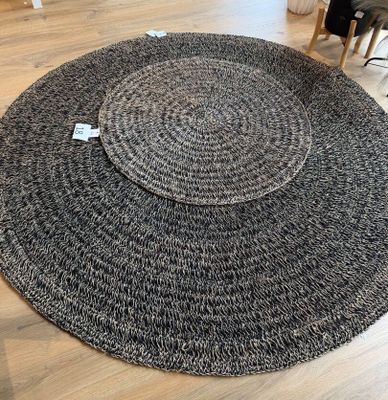 un tapis rond noir et blanc posé sur un parquet dans un salon