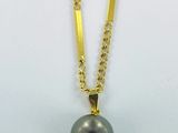 a black pearl and gold necklace on a white background