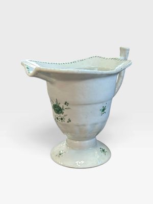 un vase blanc orné de motifs verts sur un fond blanc
