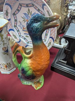 de nombreux vases de styles variés posés sur une table, avec une horloge en arrière-plan