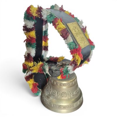 a bell with a wreath around it on a white surface