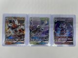 three pokemon cards in plastic cases on a white surface