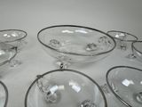 several clear glass bowls and plates are arranged on a white surface