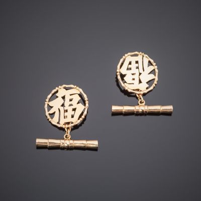a pair of gold earrings with chinese characters on them