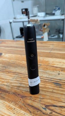une brosse à dents électrique noire posée sur une table en bois