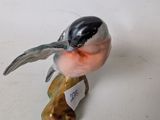 figurine of a bird sitting on a branch with a tag on it