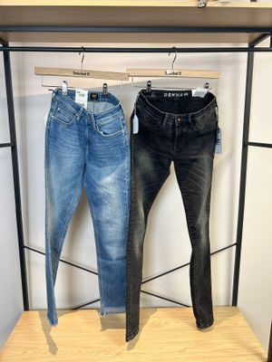 deux paires de jeans suspendues à un portant dans un magasin de vêtements